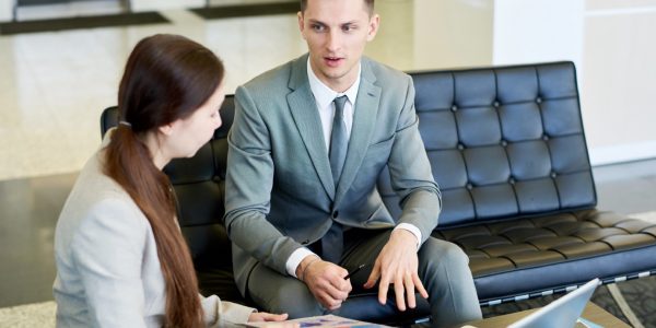Portrait of successful young businessman  talking to young woman during meeting sitting at coffee table in office, copy space